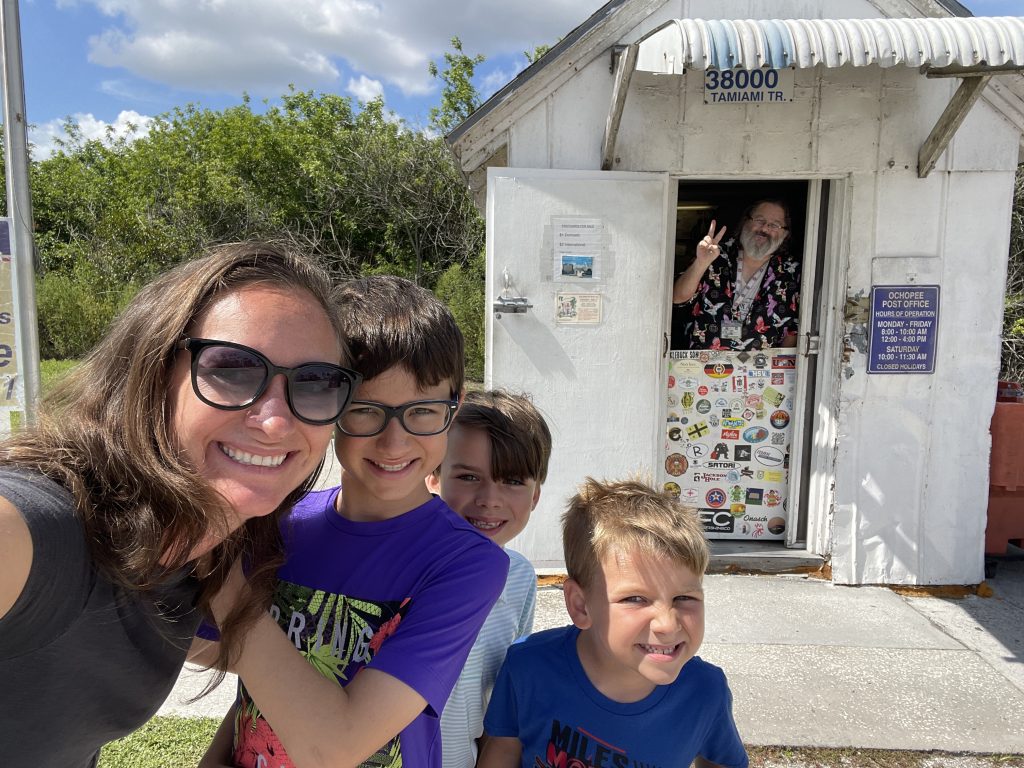 Family poses in front of the Ochopee Post Office- the smallest post office in the United States. 